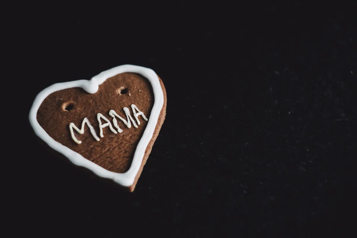 Galleta en forma de corazón con un nombre escrito en glasa blanca, sobre fondo negro
