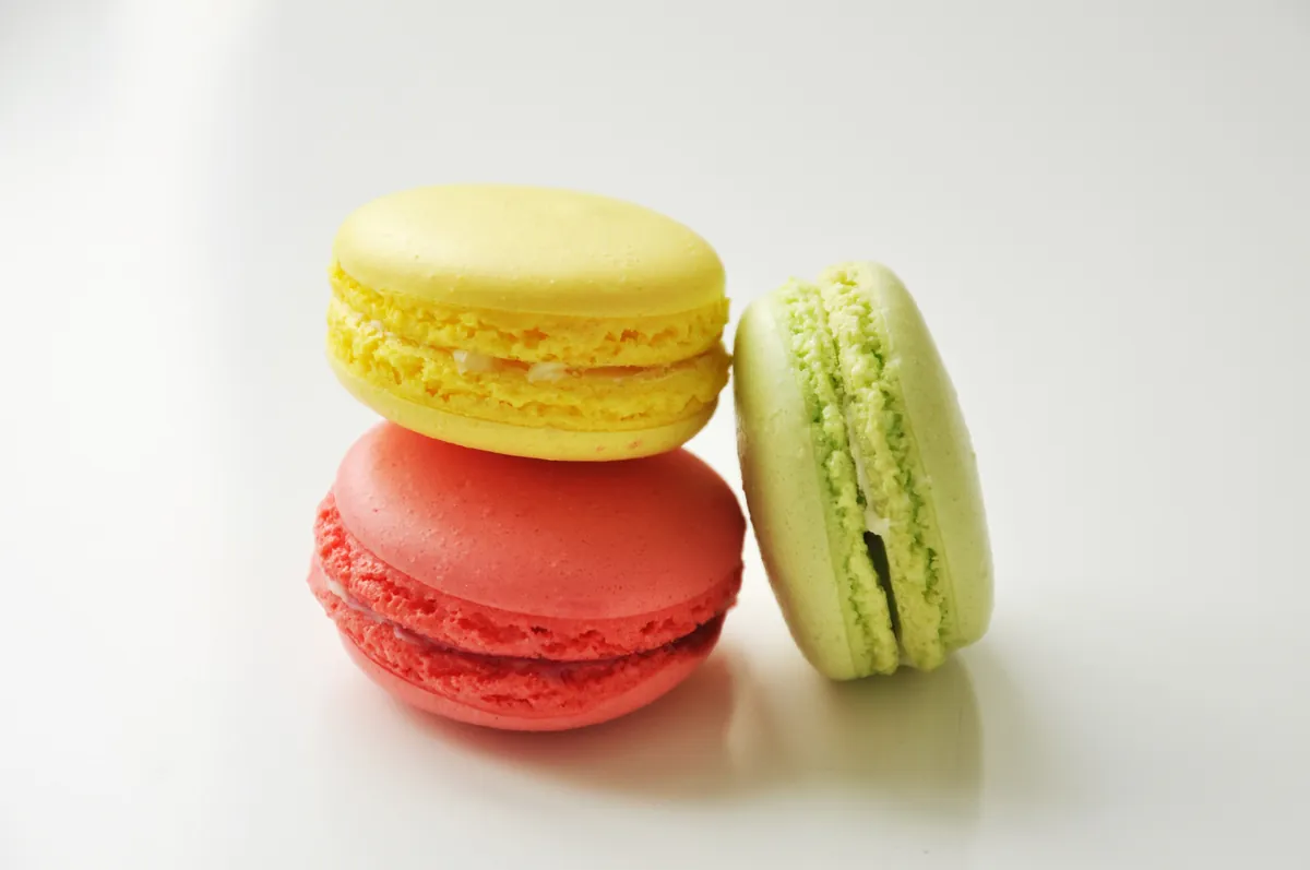 Tres macarons, amarillo, rojo y verde, sobre fondo blanco